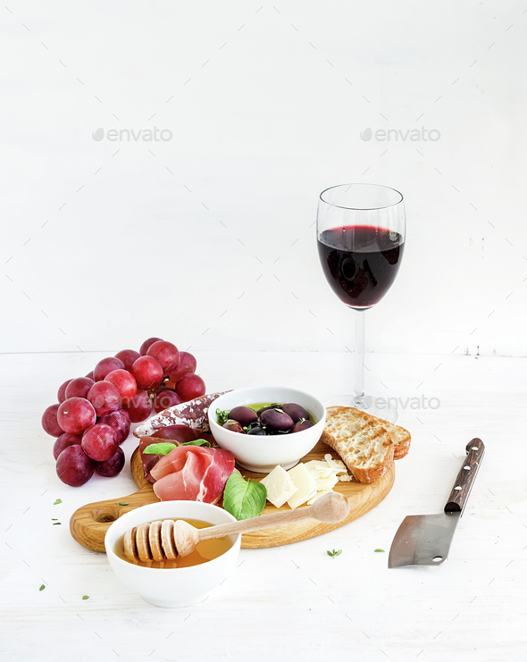 Wine appetizer set. Glass of red, grapes, parmesan cheese, meat variety