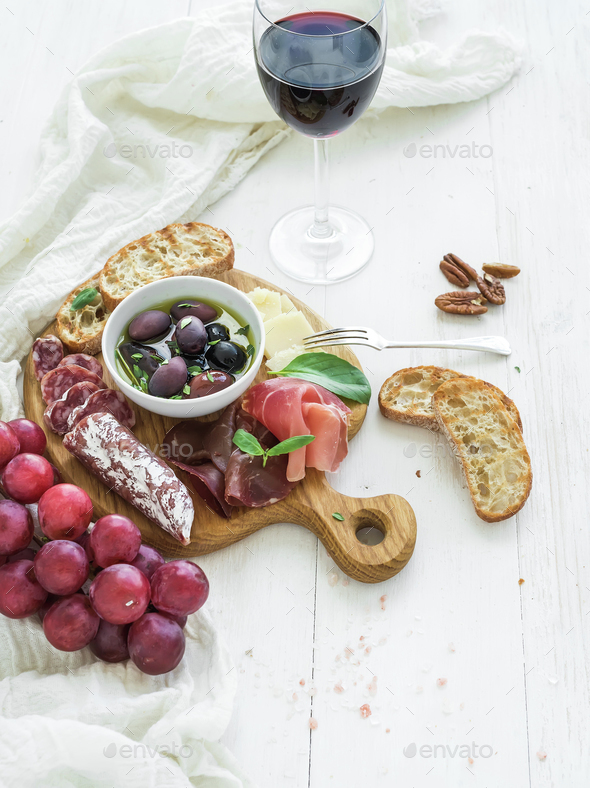 Wine appetizer set. Glass of red, grapes, parmesan cheese, meat variety, bread slices, pecan nuts