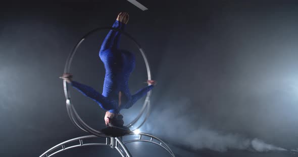 Headstand in a Spinning a Steel Hoop By an Athletic Woman in Blue Costume alt