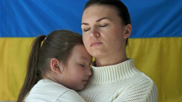 Young Woman with Her Daughter on the Background of the Flag of Ukraine alt
