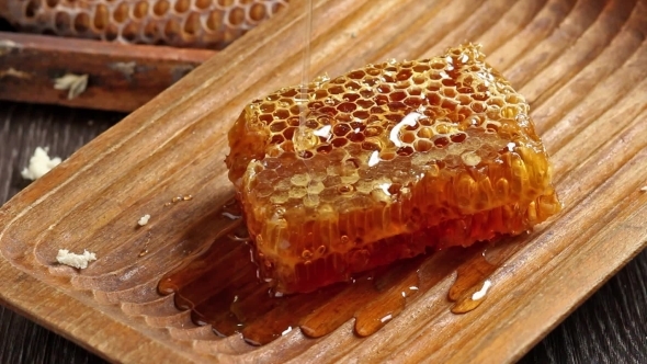 Honeycombs With Pouring Honey From Wooden Honey Dipper