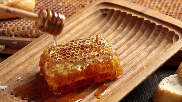 Honeycombs With Pouring Honey From Wooden Honey Dipper