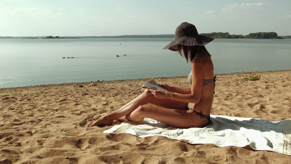 Young Woman Reading Book At The Beach