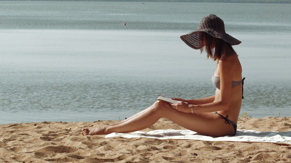 Young Woman In Bikini Reading Book At The Beach