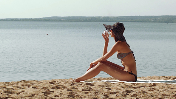 Relaxing Woman Drinking On The Sand alt