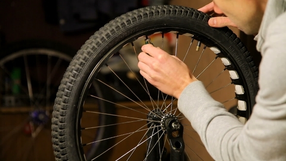 Bike Maintenance. The Young Man Tightens The Spokes On The Bicycle Wheel.