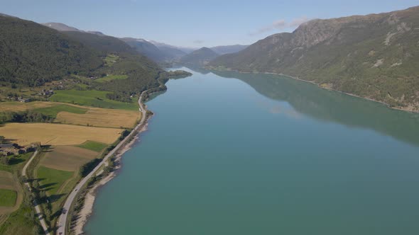 Aerial shot flying over a river snaking through a mountain valley in Norway alt