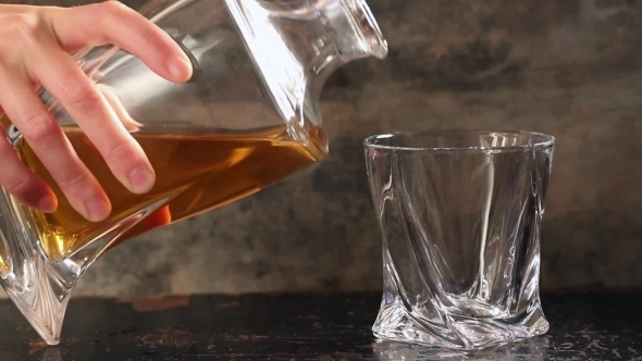 Pouring Whiskey From Bottle To Glass Over Gray Background