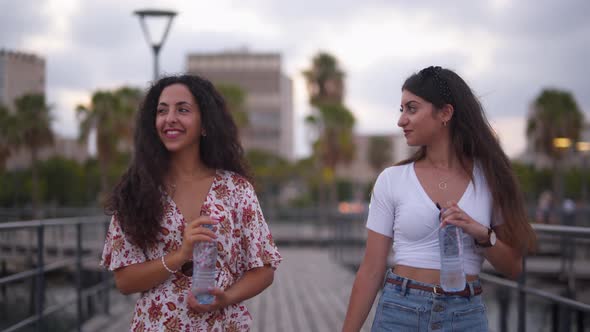 Young Hipster Women Walking on Pier and Drinking Water