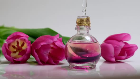 Perfumery. Drops falling from cosmetic pipette to glass bottle with perfume oil alt