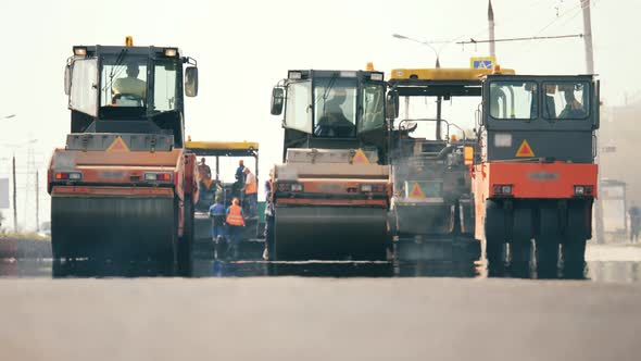 Front View of Asphalt-placing Machines and Workers. Road Construction Process. alt