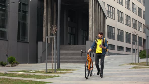 The Food Delivery Guy is Going and Talking on the Video on His Smartphone alt