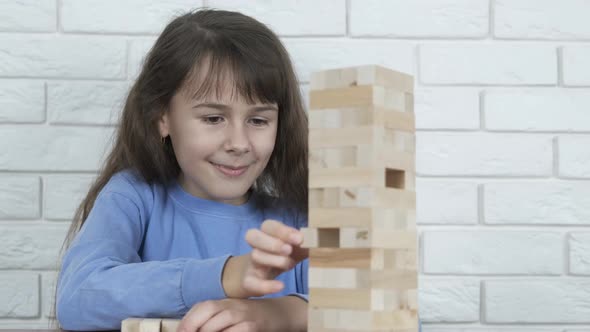 The child collapses the tower of wooden blocks. alt