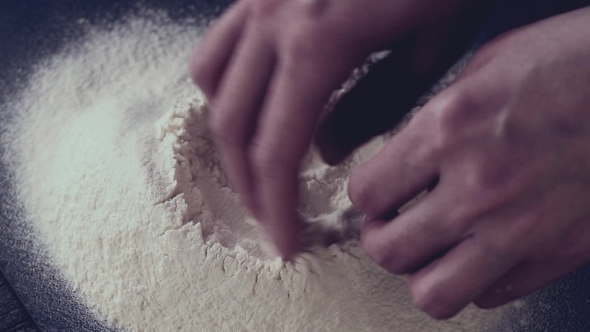Female Hands Break The Egg Into Flour