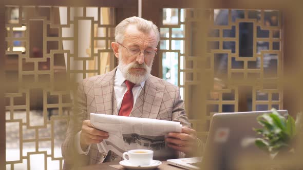 Old Businessman with Laptop at Coffee Break in His Office Concept alt