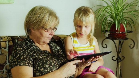 Granddaughter And Grandmother Playing On The Tablet alt