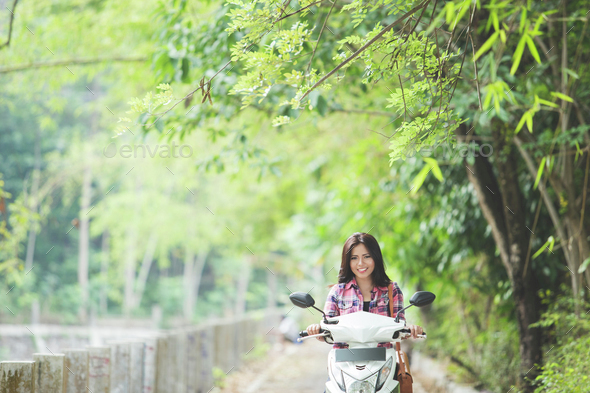 Young asian woman riding a motorcycle in a park