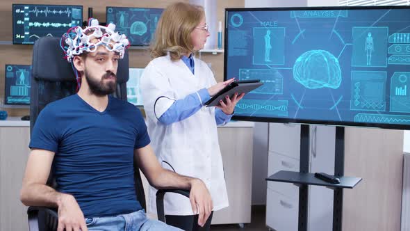 Female Neurologist Reading Data From Brainwave Scanning Headset alt