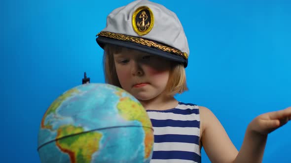Little Blond Girl in Sailor Hat is Pointing Her Finger Into the Globe alt