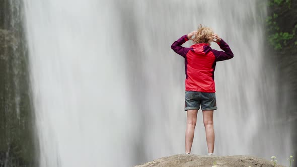 Hiking Woman in Red Jacket Near Big Waterfall