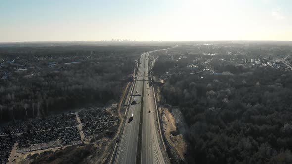 Drone View of Contemporary Asphalt Roadway with Running Cars Going Among Green Forest Near City