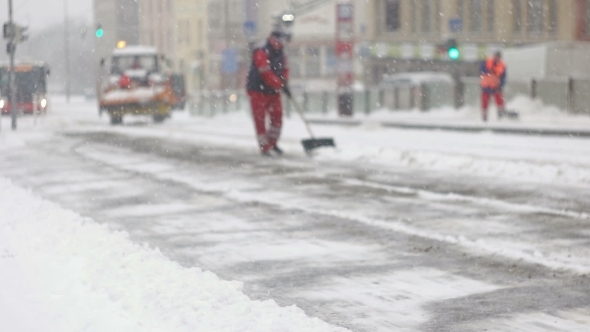 Squad Of City Workers Cleaning Snow From Station