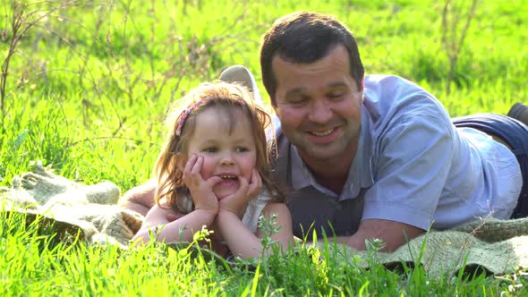 Happy Father and Daughter Resting on the Grass alt