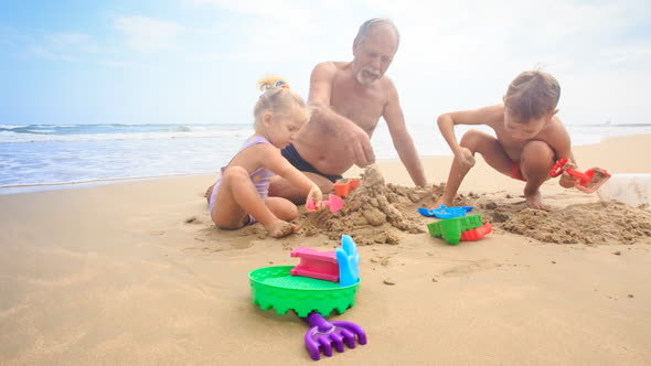 Grandpa Kids Build Sand Castle on Beach by Wave Surf alt