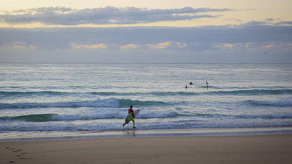 Surfer Running along Beach and into the Water for a Sunrise Surf