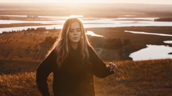 Young Woman in Black Clothes Training with a Sword While Sunset on Nature alt