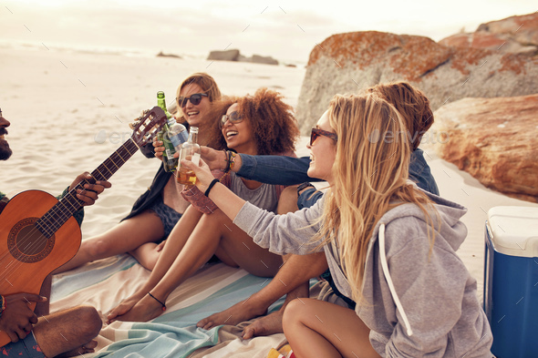 Multi-ethnic friends enjoying beverages on the beach - Stock Photo - Images