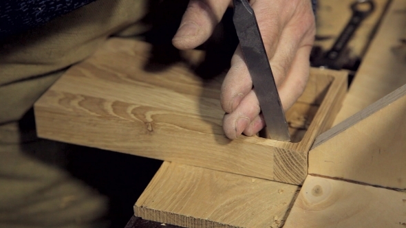 A Man Works a Chisel With a Tree