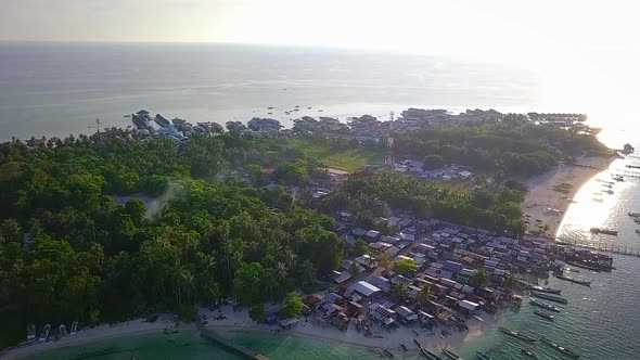 Aerial flight towards forest and village on island in Malaysia, wide distance shot moving forward in alt