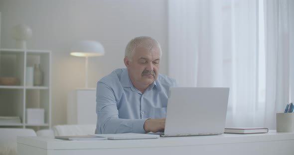 Aged Man Is Feeling Overextension and Fatigue of Neck During Working with Laptop, Rubbing Muscles alt