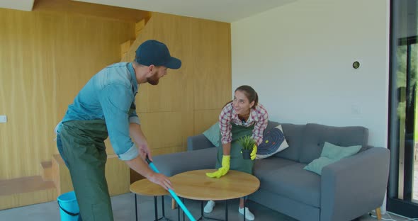 Positive Smiling Professional Cleaners Doing Cleanup in Ordinary Apartment. alt