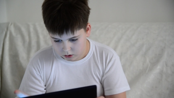 Teen Boy Enjoys  Tablet Indoors