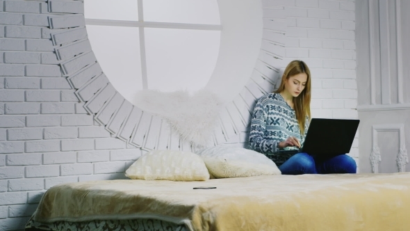 An Attractive Young Woman Uses a Laptop At Home alt