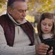 Caucasian grandfather with girl using mobile phone at the park. Shot with RED helium camera in 4K - VideoHive Item for Sale