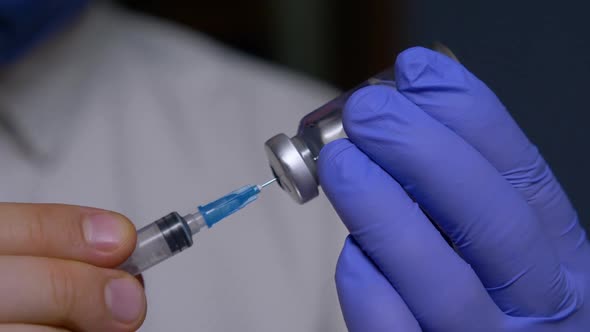 Unrecognizable Nurse Draws Solution Into Syringe with Needle From Vial