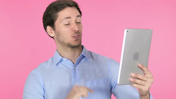 Online Video Chat on Tablet by Young Man on Pink Background alt