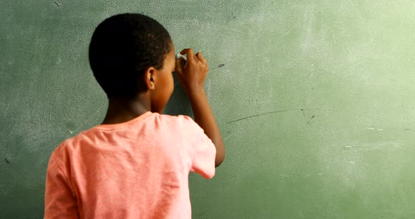 Schoolboy doing mathematics on chalkboard in classroom 4k alt
