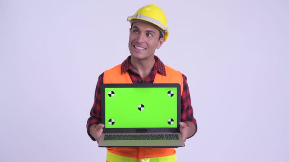 Young Happy Hispanic Man Construction Worker Thinking While Showing Laptop