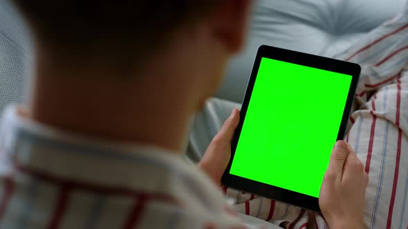 Man Holding Tablet Videocalling in Pajamas Closeup alt