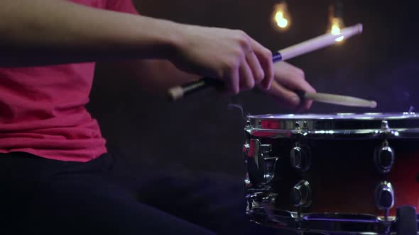 The drummer plays the snare drum with sticks close up.