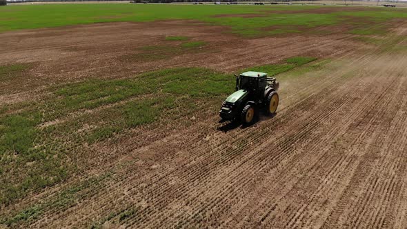 Aerial View of a Tractor with a Mower Mows the Grass on an Empty Field. Field Preparation and alt