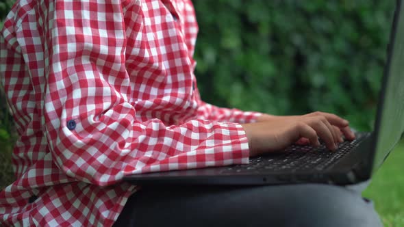 Closeup of Small Female Hands Working on a Laptop Keyboard Girl Sitting on the Grass Outside in the alt