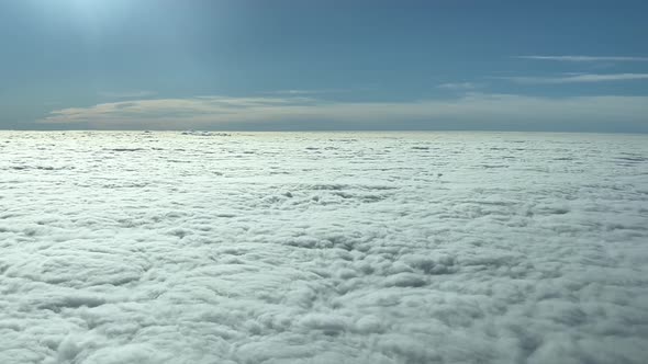 Cumulus dense clouds with sunny clear sky from above. Airplane pov shot. Wide cloudscape view from u alt