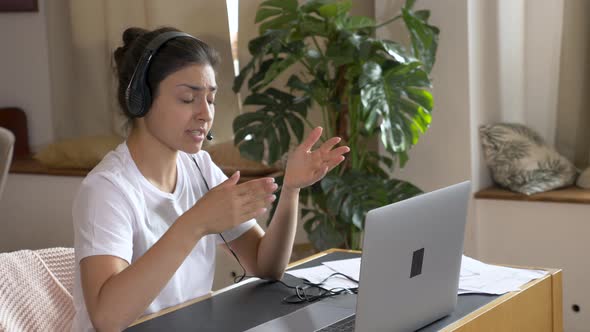 Young indian business woman wearing headphones communicating by video call alt