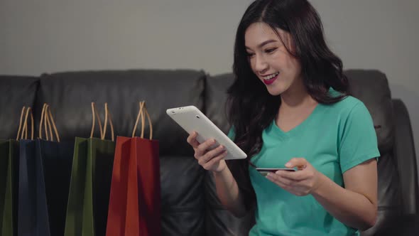 happy woman using digital tablet for online shopping with credit card in the living room