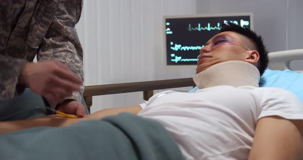 Military Medic Giving Injured Patient Intravenous Drip Injection in Hospital Ward alt